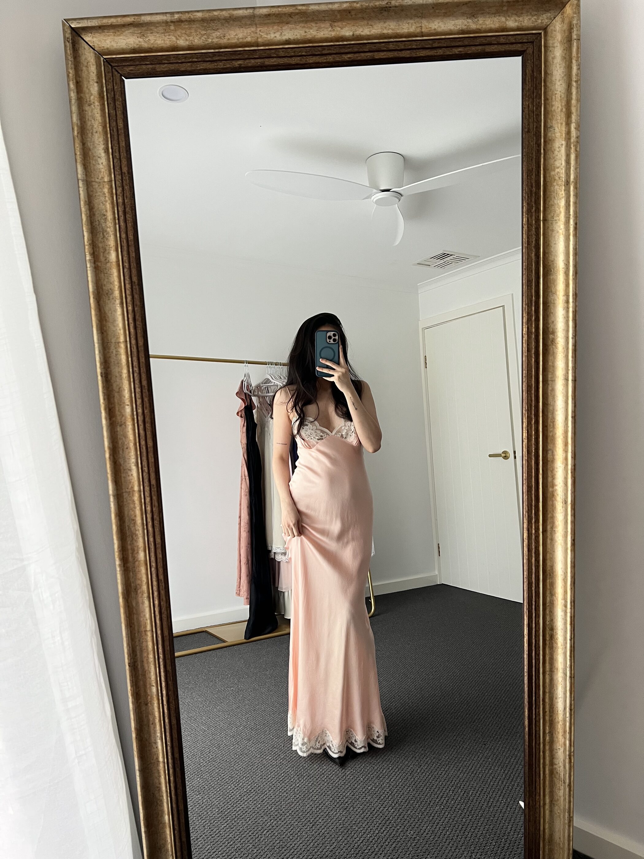 Blush bias-cut silk gown with a lace hem, worn, seen in a gilt mirror